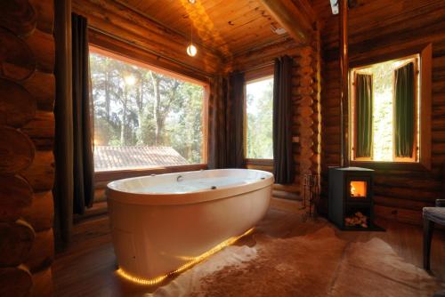 eine Badewanne in einem Raum mit einem großen Fenster in der Unterkunft Estalagem Wiesbaden in Monte Verde