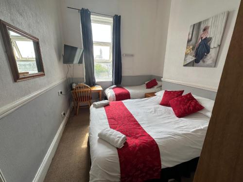 a bedroom with two beds with red pillows at Tuxford House in Blackpool