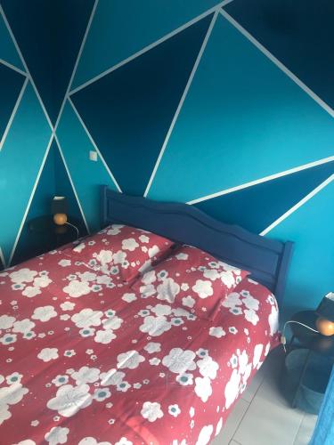 a bedroom with a bed with a red bedspread with flowers at petite maison calme in Hourtin