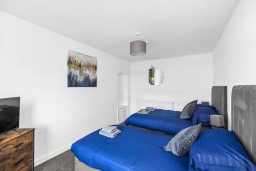 a bedroom with two blue beds and a tv at Spacious and Peaceful 4BR 2Bathroom Near Montrose Port in Ferryden