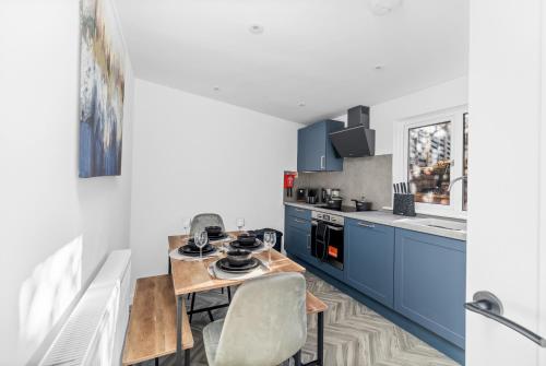 a kitchen with blue cabinets and a table and chairs at Spacious and Peaceful 4BR 2Bathroom Near Montrose Port in Ferryden
