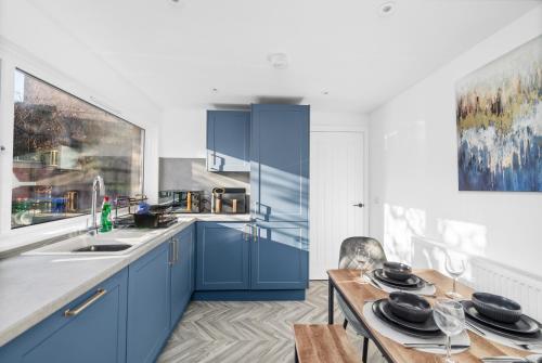 FerrydenにあるWild Berry Stays- Ferrydenのキッチン(青いキャビネット、木製テーブル付)