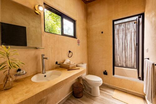 a bathroom with a sink and a toilet and a window at Xtambaa Selva in Tulum