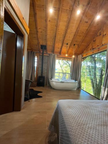 a bedroom with a bath tub and a large window at Chalé Refúgio Panorâmico in Canela