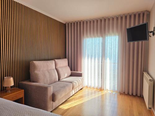 a bedroom with a couch and a television in a room at Hotel Miracastro in Castro Laboreiro