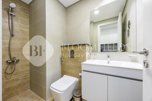 Un baño con inodoro, lavabo y espejo. en Bloomfields Elegant Pool View Stu The Gate, en Abu Dhabi Intl
