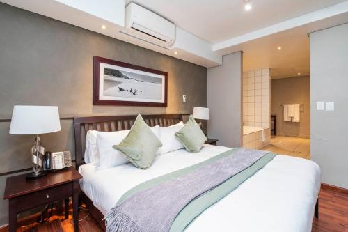 a bedroom with a large white bed with a nightstand and a bed sidx sidx at Hint of Luxury at Circa in Cape Town