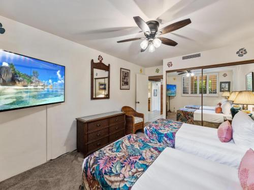 a bedroom with two beds and a flat screen tv at Polo Beach Club 102 in Wailea