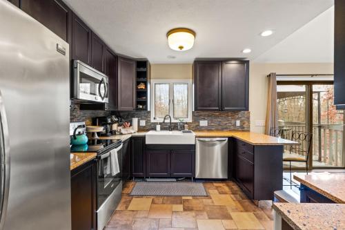 a kitchen with dark wood cabinets and stainless steel appliances at Cozy Mountain Song- Massanutten Mountain in McGaheysville