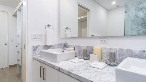 a white bathroom with a sink and a mirror at Encantame Towers Viento 304 in Playa Encanto
