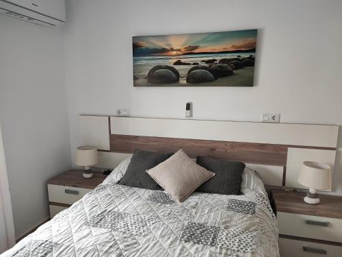 ein Schlafzimmer mit einem Bett und zwei Lampen und einem Gemälde an der Wand in der Unterkunft Geani in La Marina