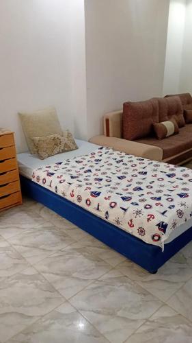a bed in a living room with a comforter on it at Appartement S1 Tulipe in Zarzis