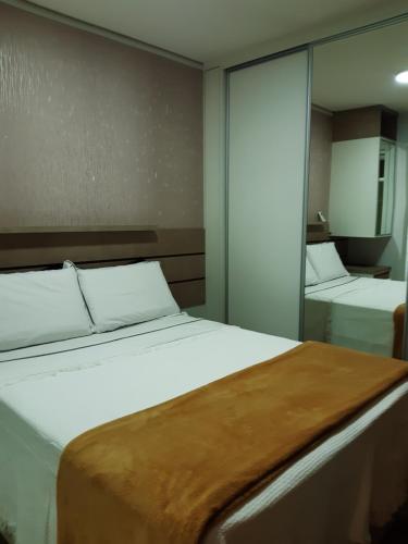 a bedroom with a large white bed and a mirror at Flat particular Vision Executive in Brasília