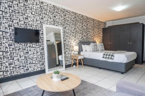 a bedroom with a bed and a tv on a brick wall at City Oasis Suite Cape Town in Cape Town