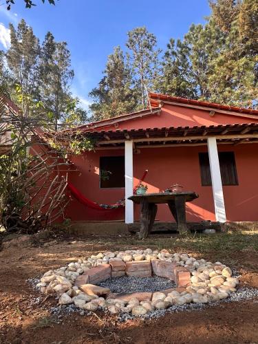 a red house with a picnic table in front of it at Chalé Moinho Localização Privilegiada em Carrancas - MG in Carrancas