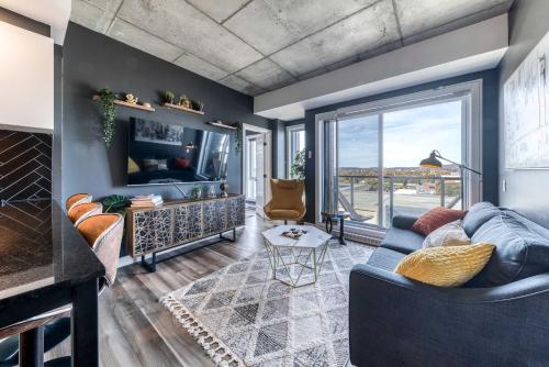 a living room with a blue couch and a tv at Appartement Luxe, Incredible Sunset View, Pool, Parking, Near Old Québec in Quebec City