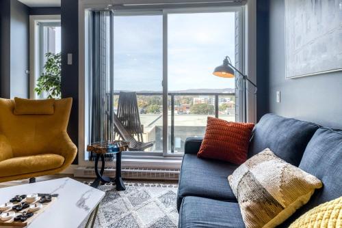 a living room with a blue couch and a large window at Appartement Luxe, Incredible Sunset View, Pool, Parking, Near Old Québec in Quebec City