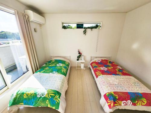 two beds in a small room with a window at 水族館に近いゆったり別荘-Ent Terrace Okinawa in Motobu