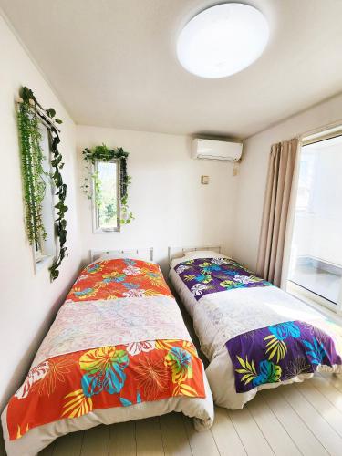 two beds sitting next to each other in a bedroom at 水族館に近いゆったり別荘-Ent Terrace Okinawa in Motobu