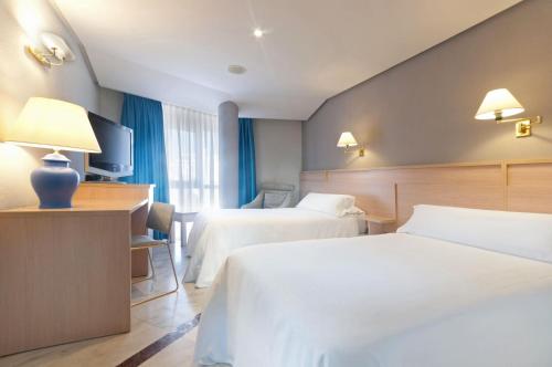 une chambre d'hôtel avec deux lits et une télévision dans l'établissement Hotel Puertollano, à Puertollano