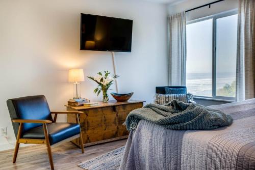 Ocean Front with Spectacular Views! 2 Bedroom, 2 Bath! Seal Rock Cottage! في Seal Rocks: غرفة نوم بها سرير وكرسي وتلفزيون