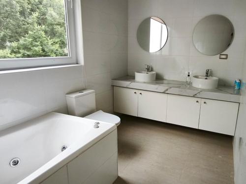 トゥンケンにあるConcrete house overlooking the ocean and beach accessの洗面台2つ、浴槽1つ、鏡1つを備えたバスルーム