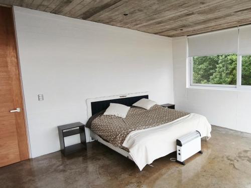 トゥンケンにあるConcrete house overlooking the ocean and beach accessのベッドと窓のある白い寝室