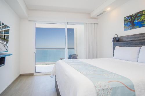 a bedroom with a bed and a large window at Splash in The New Lazy River and Sleep In Luxury Encantame Towers Velero 2202 in Playa Encanto