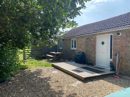 a wooden deck next to a brick building with a white door at Little Owls Nest Holiday Home in Wisbech