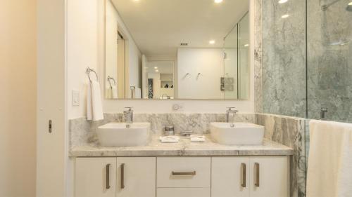 a bathroom with two sinks and a shower at Encantame Towers Viento 1103 in Playa Encanto