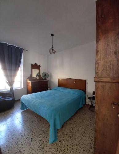 a bedroom with a blue bed and a dresser and a window at Cà Giaculn in Muriaglio