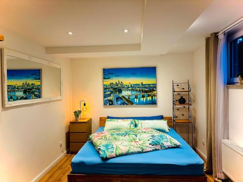a bedroom with a blue bed with two paintings on the wall at Skylineblick Doppelzimmer in einer 2 Zimmer-Ferienwohnung mit Gemeinschaftsbereichen wie Wohn-Küchenbereich sowie Bad und WC in Seligenstadt