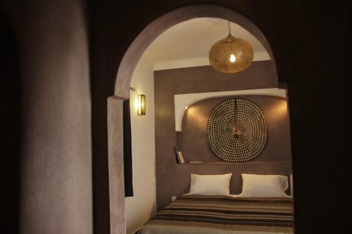 een slaapkamer met een bed in een kamer met een boog bij Riad Miliana in Marrakesh