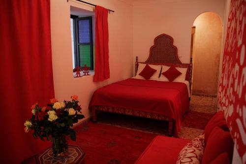 een slaapkamer met een rood bed en een vaas met bloemen bij Riad Miliana in Marrakesh