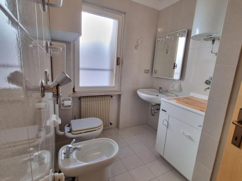 a bathroom with a sink and a toilet and a window at Villa Erica in Alba di Canazei