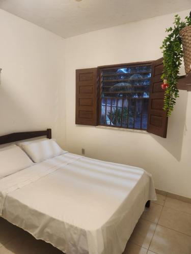 a bedroom with a white bed and a window at Kitnet Quintal verde in Itacaré