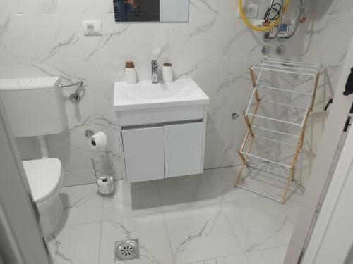 a white bathroom with a toilet and a sink at Apartman Lazar in Ruma