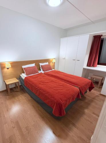 a bedroom with a large bed with a red blanket at Premium Chalet huoneisto kylpylän vieressä in Vierumäki