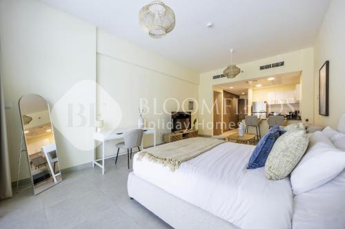 a bedroom with a white bed and a dining room at Bloomfileds Cozy Stu in Park View in Abu Dhabi