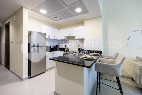 a kitchen with white cabinets and a black counter top at Bloomfileds Cozy Stu in Park View in Abu Dhabi