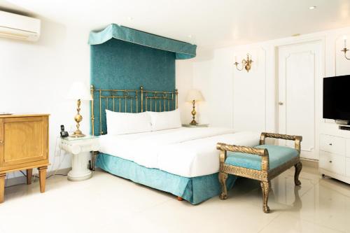 a bedroom with a bed and a chair and a tv at Ébano by PB - Palacio Borghese in Oaxaca City