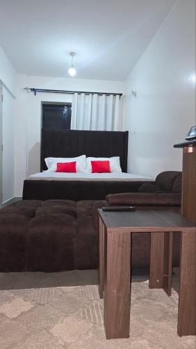 a bedroom with a bed with red pillows and a couch at Serenity Brown Pad in Kiambu