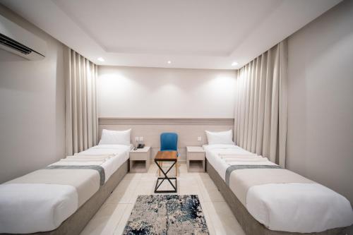 メッカにあるOrvana Al Naseem Hotelの青い椅子付きの部屋のベッド1列