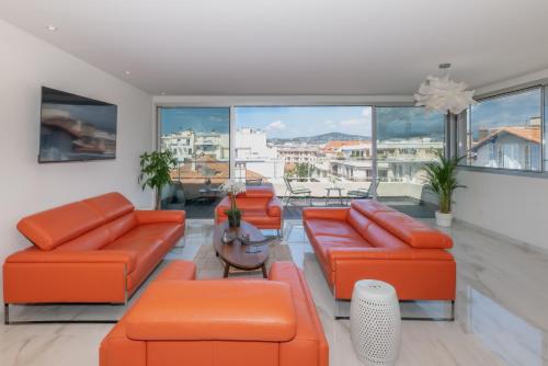 a living room with orange furniture and large windows at Sweett - Maison Blanche in Juan-les-Pins