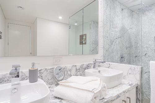 ein weißes Badezimmer mit Waschbecken und Spiegel in der Unterkunft Splash in The New Lazy River and Sleep In Luxury Encantame Velero 1103 in Playa Encanto