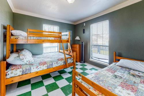 a bedroom with two bunk beds and a checkered floor at Escape Gulf Views Large Deck Pet Friendly in Crystal Beach