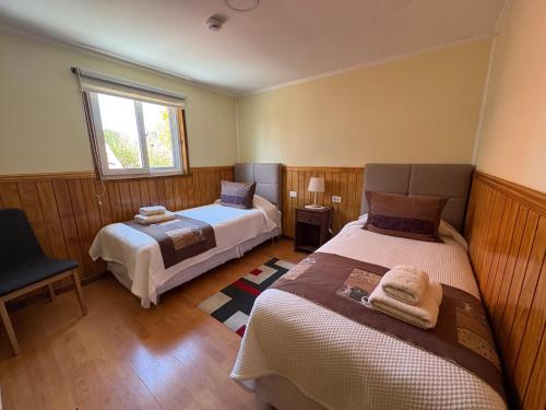 a bedroom with two beds and a window at Hostal America en Puerto Natales in Puerto Natales