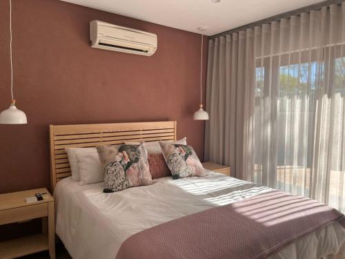 a bedroom with a bed with pillows and a window at 18 On Louvre Guesthouse in Paarl