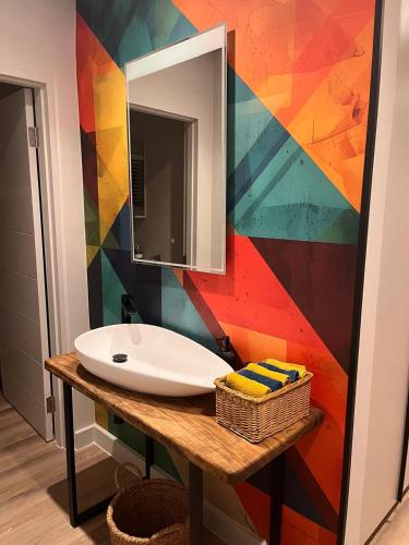 a bathroom with a sink and a colorful wall at 18 On Louvre Guesthouse in Paarl