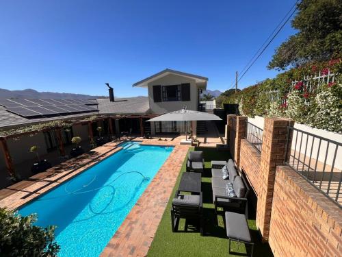 a swimming pool with chairs and an umbrella next to a house at 18 On Louvre Guesthouse in Paarl